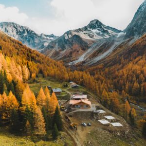 Das Glödis Refugium in Kals am Großglockner im Herbst mit gelb gefärbten Lärchen und dem Glödis im Hintergrund